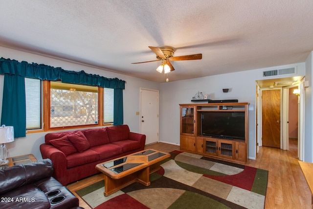 living room featuring a textured ceiling, light hardwood / wood-style flooring, and ceiling fan