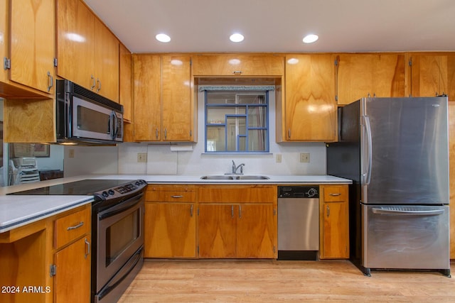 kitchen featuring decorative backsplash, sink, black appliances, and light wood-type flooring