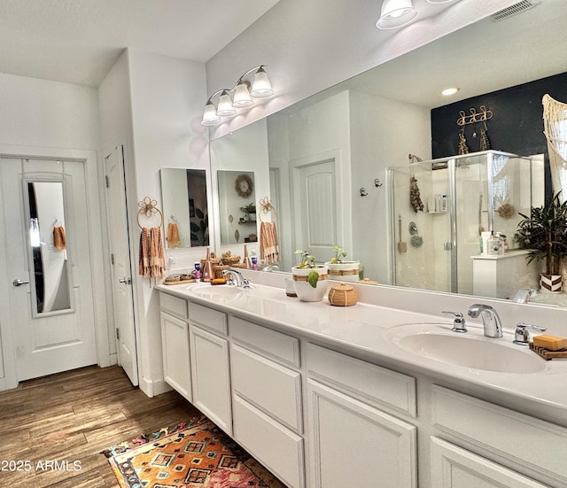 bathroom with vanity, a shower with shower door, and hardwood / wood-style floors