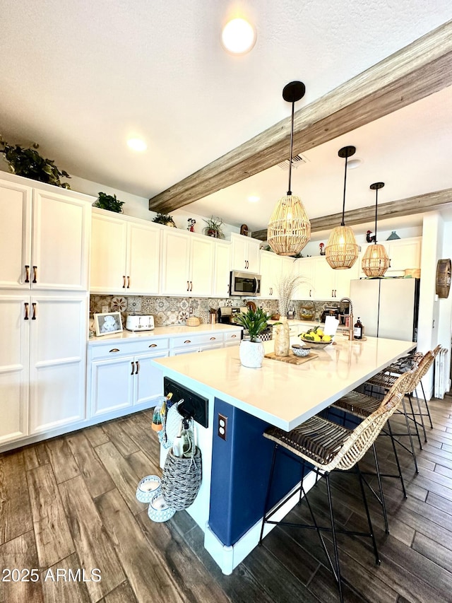 kitchen with refrigerator, white cabinetry, beam ceiling, dark hardwood / wood-style floors, and a kitchen bar