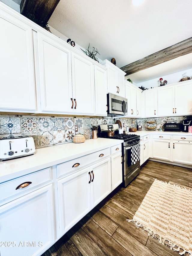 kitchen featuring beamed ceiling, white cabinets, decorative backsplash, stainless steel appliances, and dark wood-type flooring