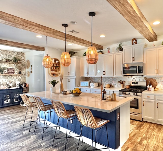 kitchen featuring light hardwood / wood-style flooring, appliances with stainless steel finishes, a kitchen island, beam ceiling, and white cabinets