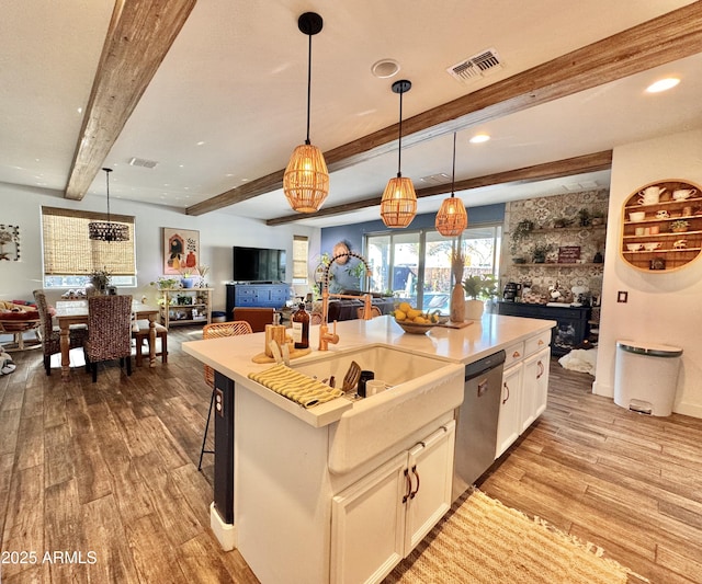 kitchen featuring white cabinetry, decorative light fixtures, dishwasher, an island with sink, and beam ceiling