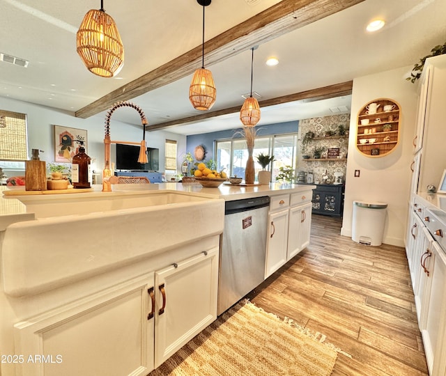 kitchen featuring dishwasher, pendant lighting, beam ceiling, light hardwood / wood-style floors, and white cabinets