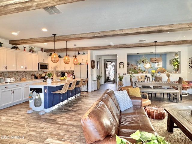 kitchen with white cabinets, decorative light fixtures, beamed ceiling, and appliances with stainless steel finishes