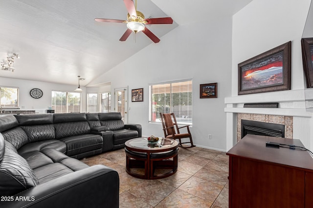 living room with vaulted ceiling, a healthy amount of sunlight, ceiling fan, and a tiled fireplace