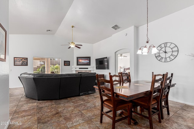 dining room featuring ceiling fan with notable chandelier and high vaulted ceiling