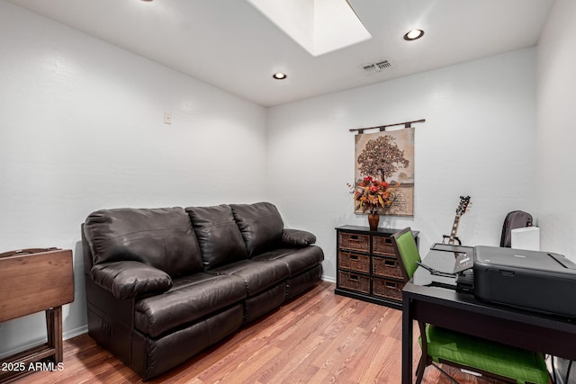 interior space with a skylight and light hardwood / wood-style floors