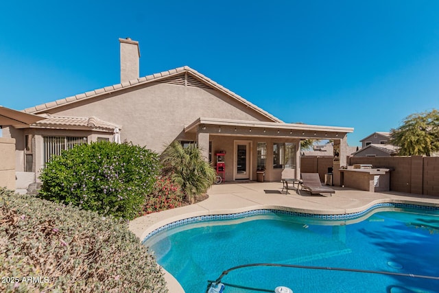 view of pool with exterior kitchen and a patio area