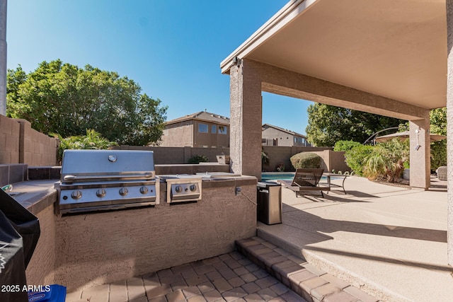 view of patio with exterior kitchen and a grill