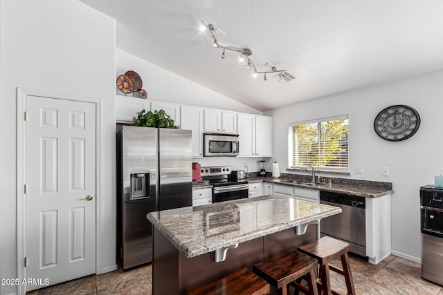 kitchen with white cabinets, sink, appliances with stainless steel finishes, and a kitchen breakfast bar