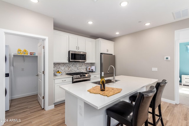 kitchen with appliances with stainless steel finishes, sink, white cabinets, and backsplash