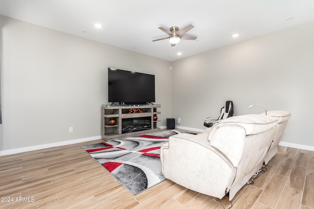 living room featuring ceiling fan, light hardwood / wood-style flooring, and a fireplace