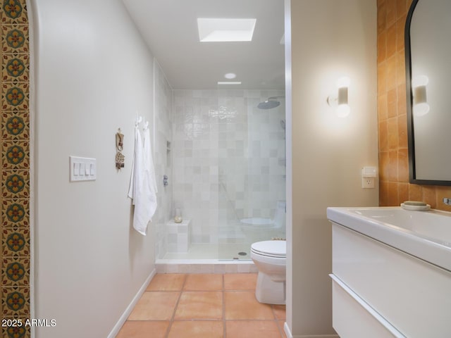 bathroom featuring a skylight, tiled shower, toilet, tile patterned floors, and vanity