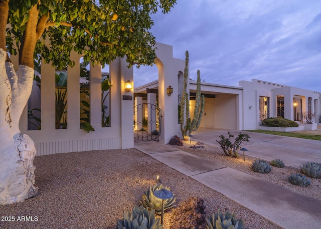 view of front of property with driveway, a gate, and stucco siding