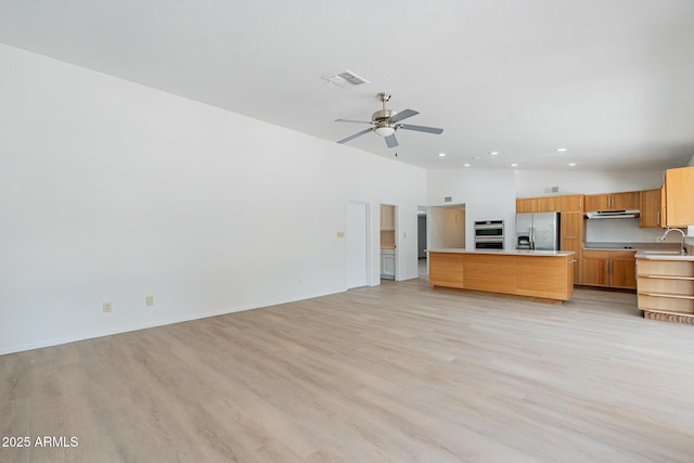 kitchen featuring ceiling fan, sink, a center island, appliances with stainless steel finishes, and light wood-type flooring