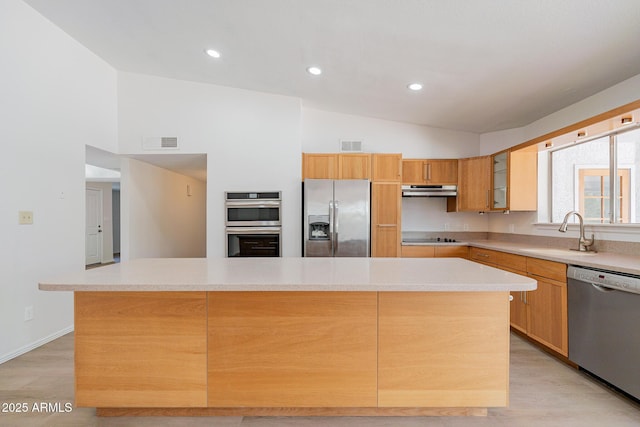 kitchen with light wood-type flooring, a center island, stainless steel appliances, and sink