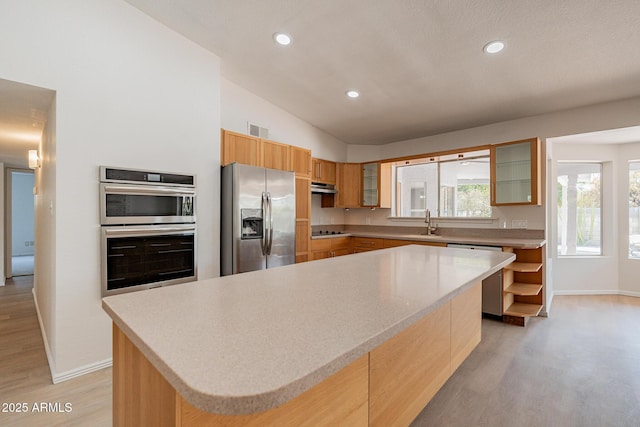 kitchen featuring sink, a center island, stainless steel appliances, lofted ceiling, and light wood-type flooring