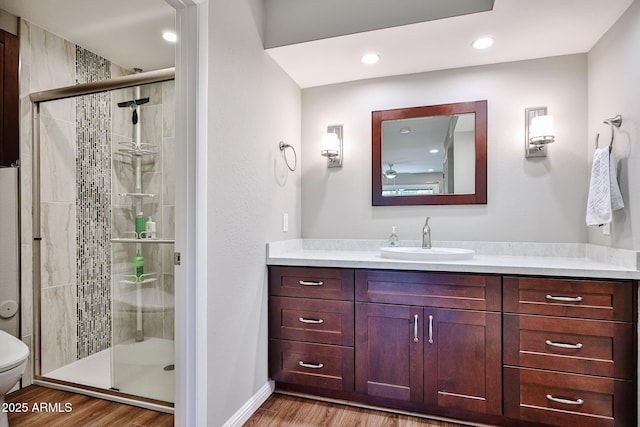 bathroom featuring vanity, a stall shower, wood finished floors, and toilet