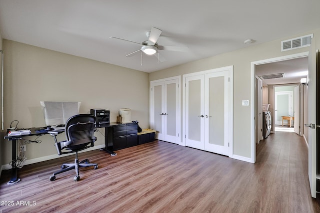 home office with visible vents, ceiling fan, baseboards, and wood finished floors