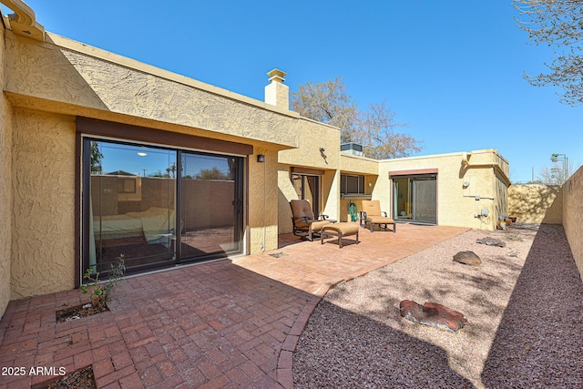 back of property with a chimney, a patio area, a fenced backyard, and stucco siding