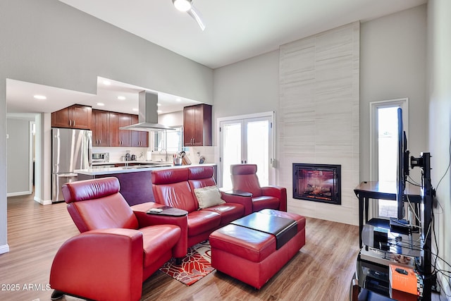 living area with a high ceiling, light wood-type flooring, and a fireplace