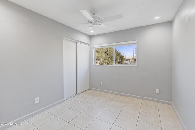 unfurnished bedroom with light tile patterned flooring, ceiling fan, and a closet