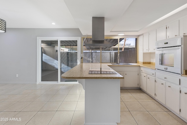 kitchen featuring white cabinetry, island range hood, white oven, and light tile patterned floors