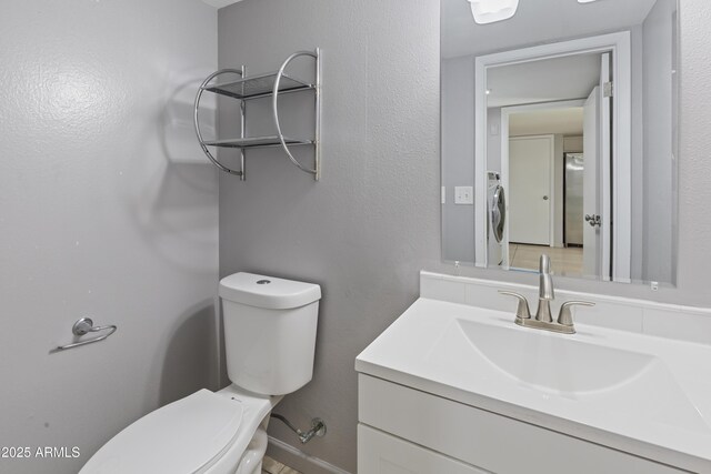 bathroom featuring vanity, washer / dryer, and toilet