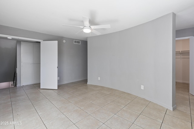 unfurnished bedroom with light tile patterned floors, ceiling fan, and a closet