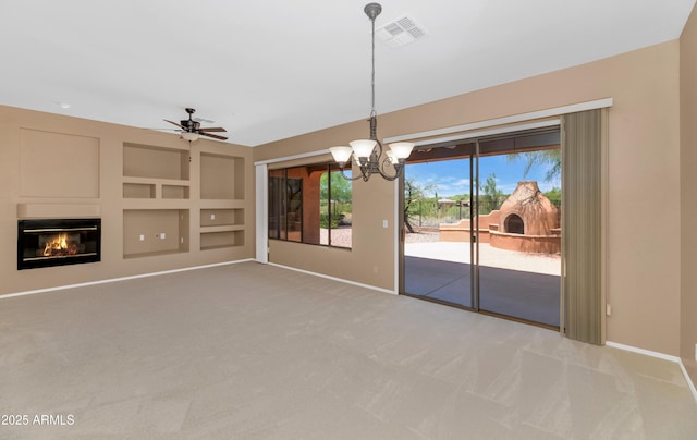 42122 N Anthem Springs Rd, Anthem, AZ 85086 - unfurnished dining area with carpet flooring, a chandelier, a glass covered fireplace, a ceiling fan, and built in shelves