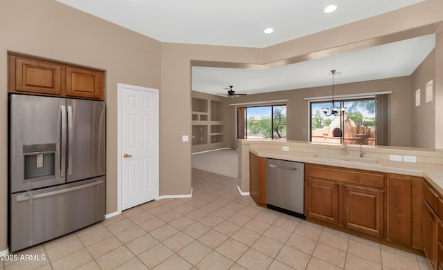 42122 N Anthem Springs Rd, Anthem, AZ 85086 - kitchen with stainless steel appliances, brown cabinets, a chandelier, light tile patterned flooring, and pendant lighting