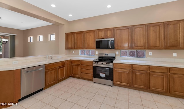 42122 N Anthem Springs Rd, Anthem, AZ 85086 - kitchen featuring stainless steel appliances, brown cabinets, a peninsula, light tile patterned floors, and recessed lighting