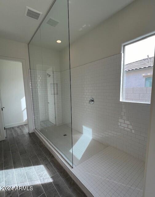 full bath featuring a tile shower, visible vents, and wood tiled floor