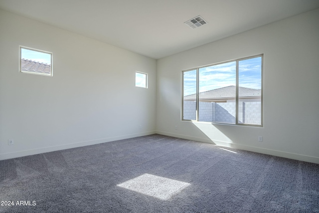 spare room with carpet floors, visible vents, and baseboards