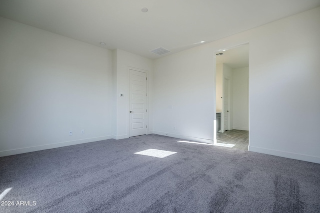 unfurnished room featuring carpet, visible vents, and baseboards