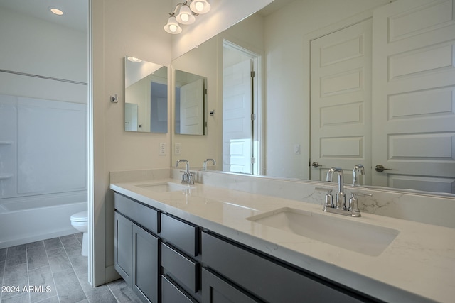 full bath featuring toilet, double vanity, and a sink