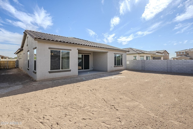 back of house featuring a fenced backyard, a tile roof, and stucco siding