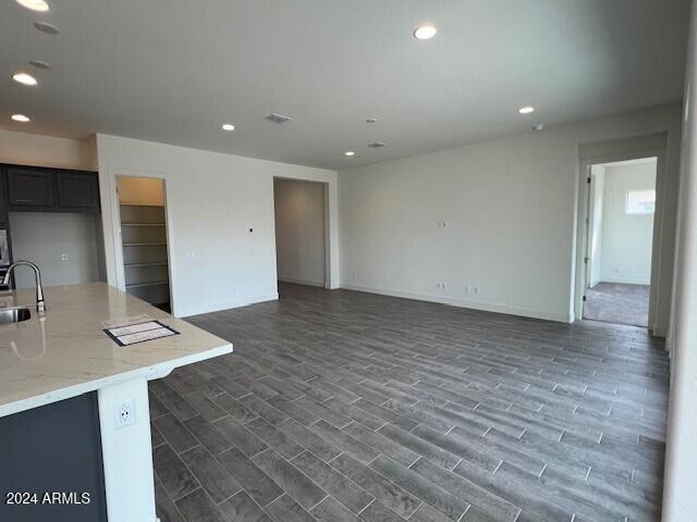 unfurnished room with dark wood-style floors, baseboards, a sink, and recessed lighting