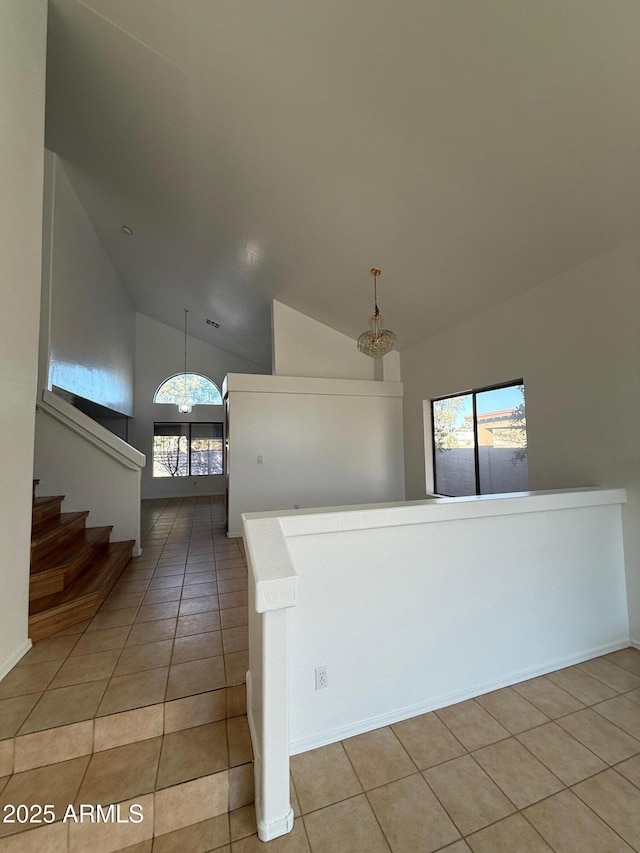 tiled entrance foyer with an inviting chandelier and high vaulted ceiling