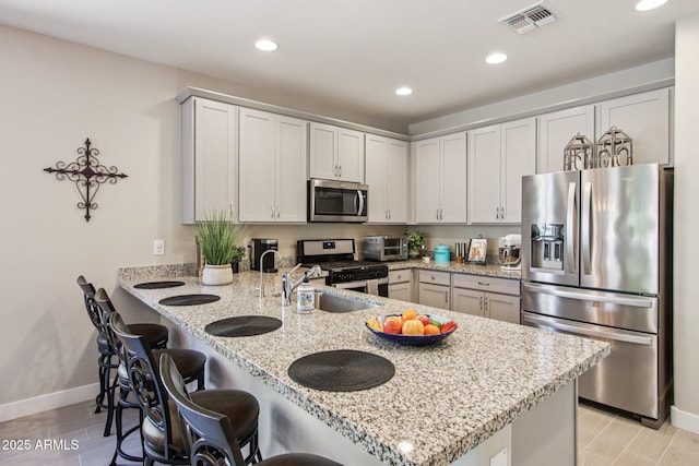 5724 N 108th Ave, Phoenix, AZ 85037 - kitchen featuring appliances with stainless steel finishes, a peninsula, recessed lighting, light stone countertops, and a breakfast bar area