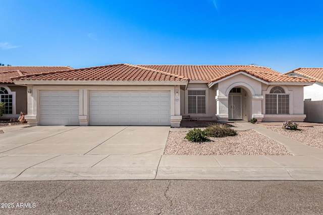 mediterranean / spanish home featuring driveway, a tiled roof, an attached garage, and stucco siding