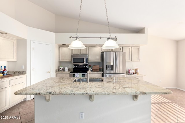 kitchen featuring light tile patterned floors, appliances with stainless steel finishes, vaulted ceiling, a sink, and a kitchen bar