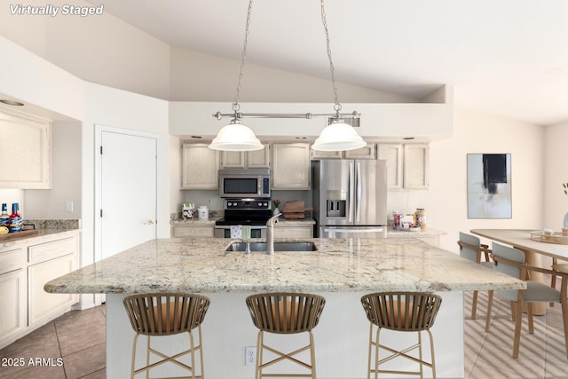 kitchen with lofted ceiling, a breakfast bar, stainless steel appliances, and a sink