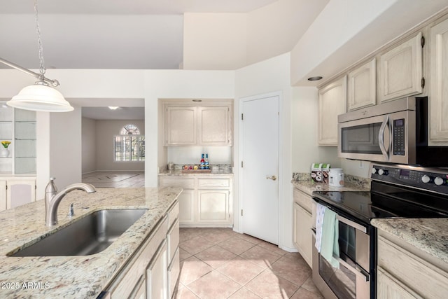 kitchen with light stone counters, decorative light fixtures, light tile patterned floors, appliances with stainless steel finishes, and a sink