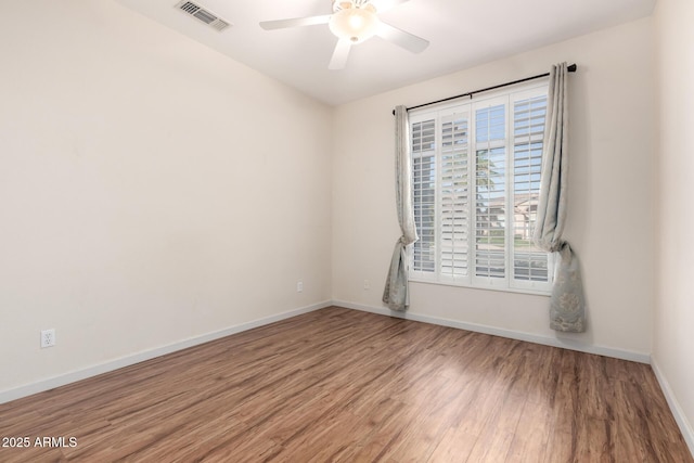 unfurnished room featuring baseboards, visible vents, ceiling fan, and wood finished floors