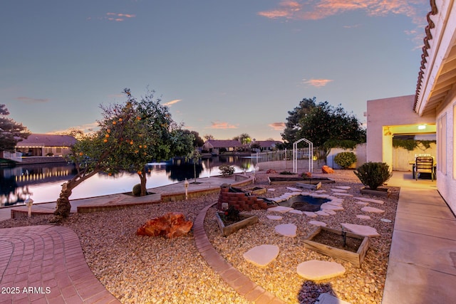 yard at dusk featuring a patio and a water view