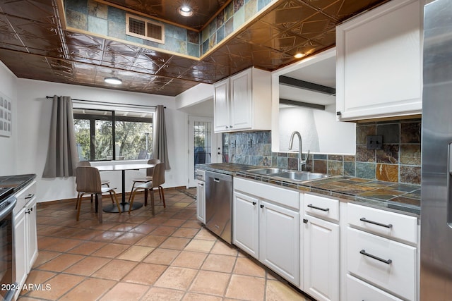 kitchen with white cabinetry, sink, tasteful backsplash, light tile patterned flooring, and appliances with stainless steel finishes