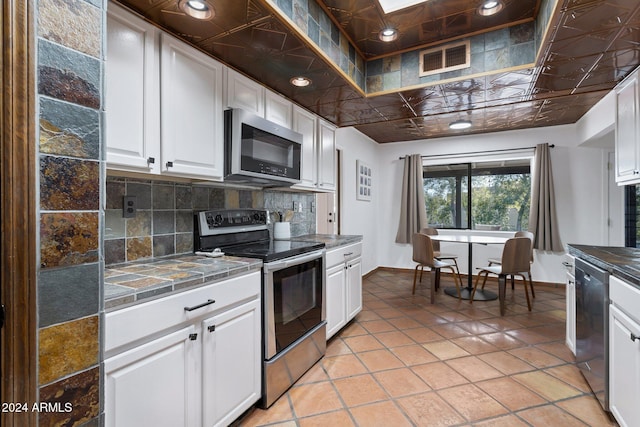 kitchen with light tile patterned flooring, white cabinetry, stainless steel appliances, and tasteful backsplash