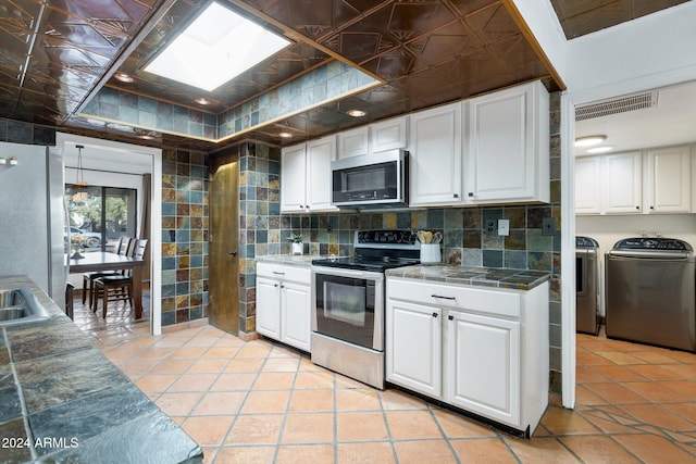 kitchen with white cabinets, light tile patterned floors, independent washer and dryer, and appliances with stainless steel finishes